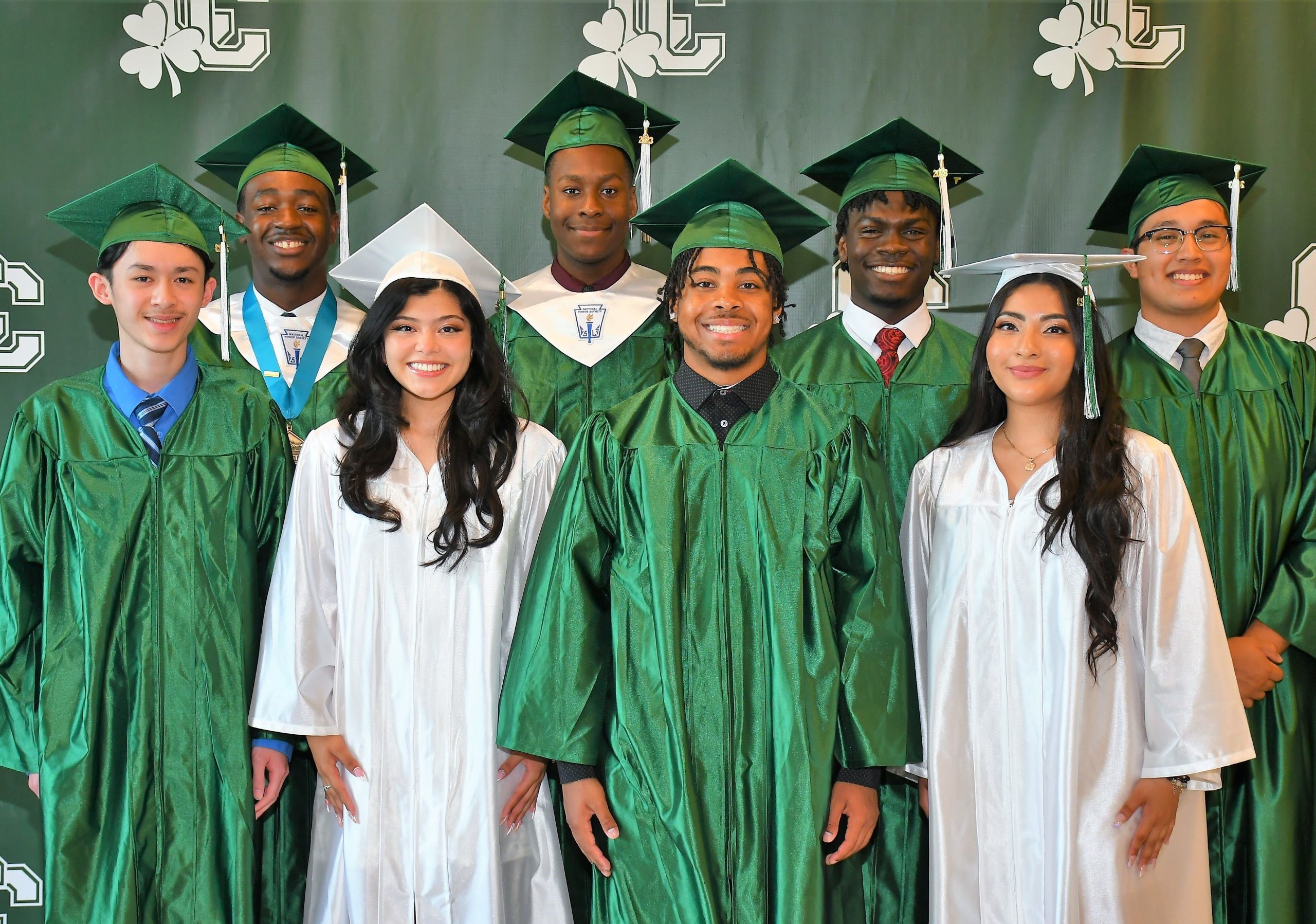 Girls in white and boys in green caps and gowns