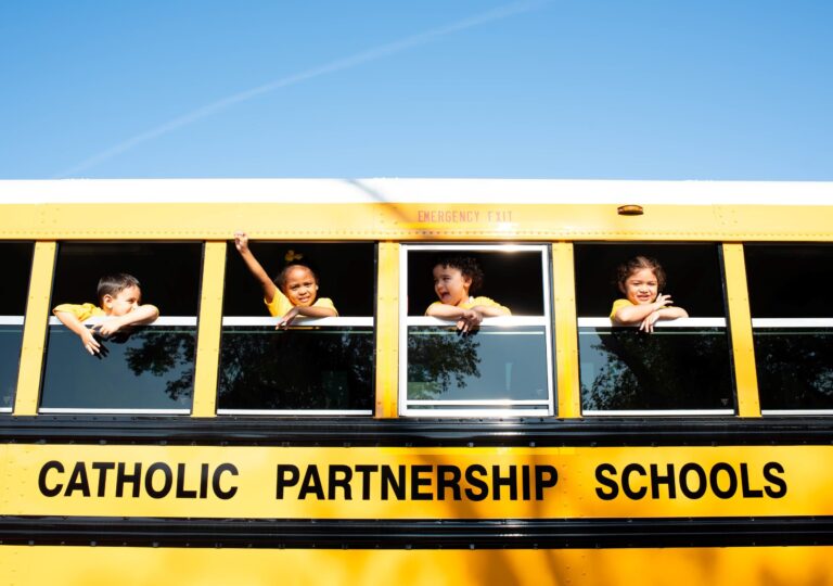 Kindergarteners waving from school bus windows